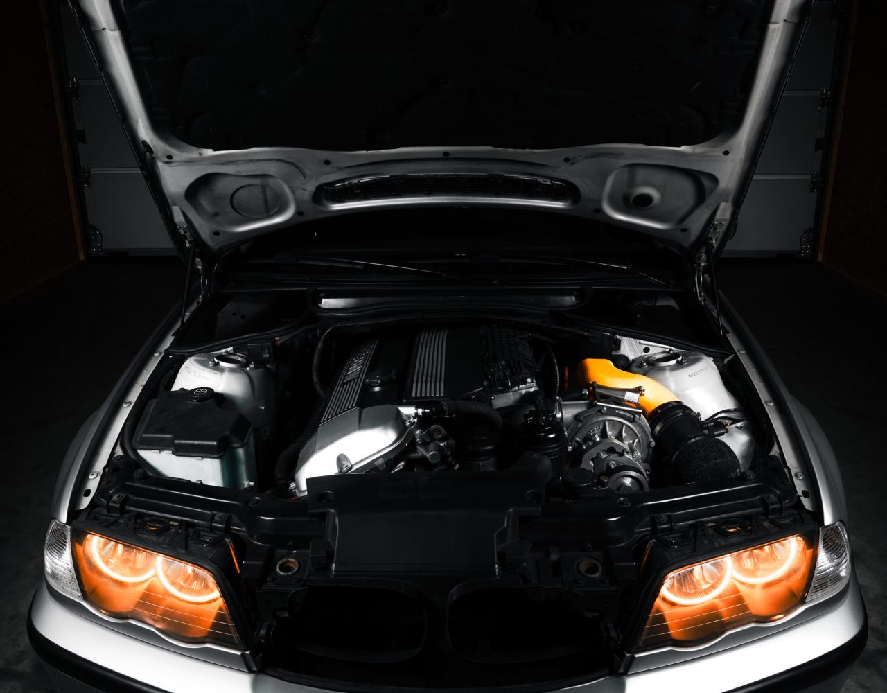 Car engine compartment with open hood on a dark background